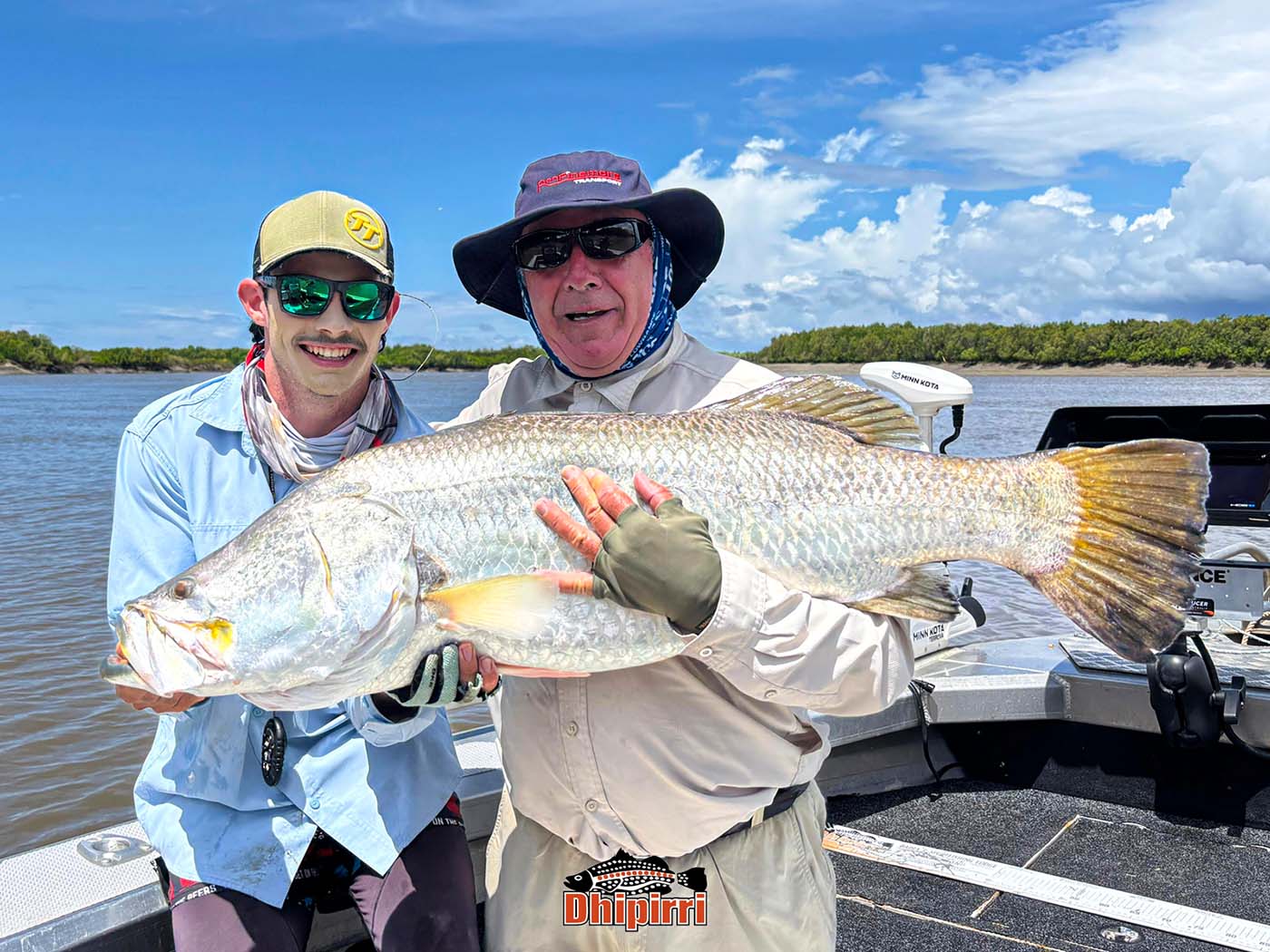Two men holding a large fish on a boat on a lake