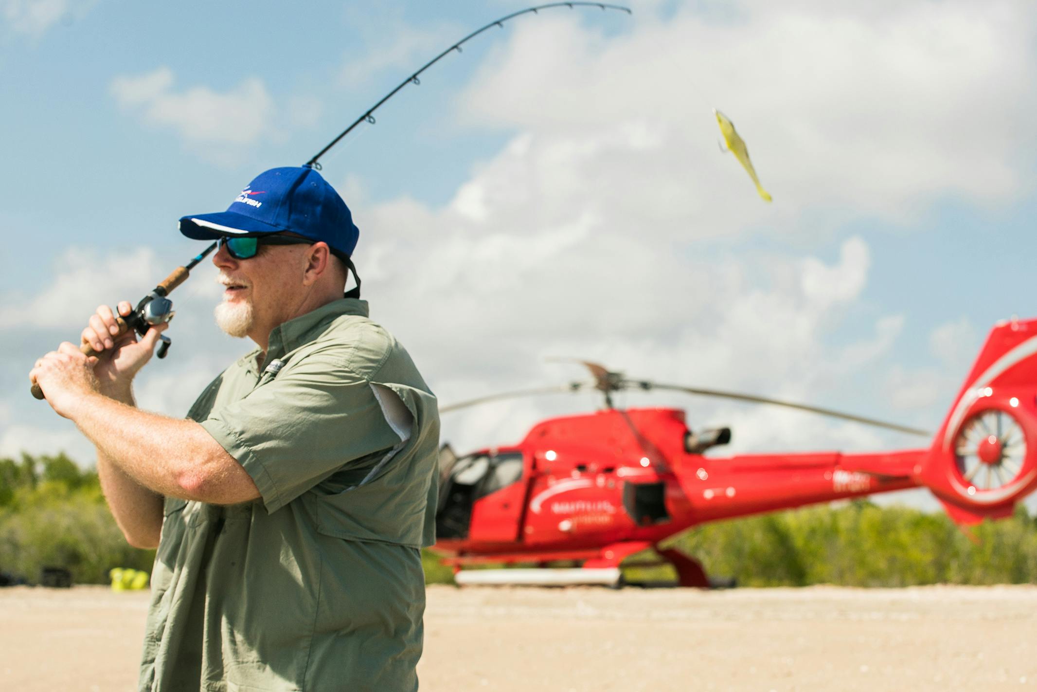 Man casting a fishing rod in front of a helicopter